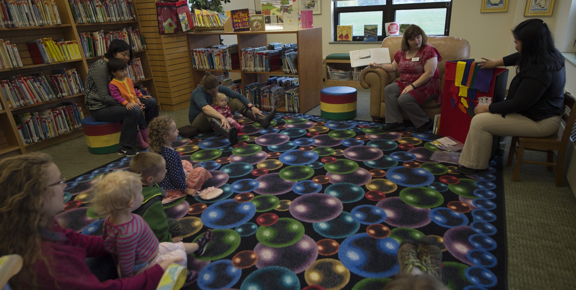 Library technicians Elida Narciso, right, shows different color fabrics while Teresa Couch reads to the children during Preschool Story Time at the Joint Base Elmendorf-Richardson, Alaska, Sept. 8, 2016. The reading theme was 'colors.'