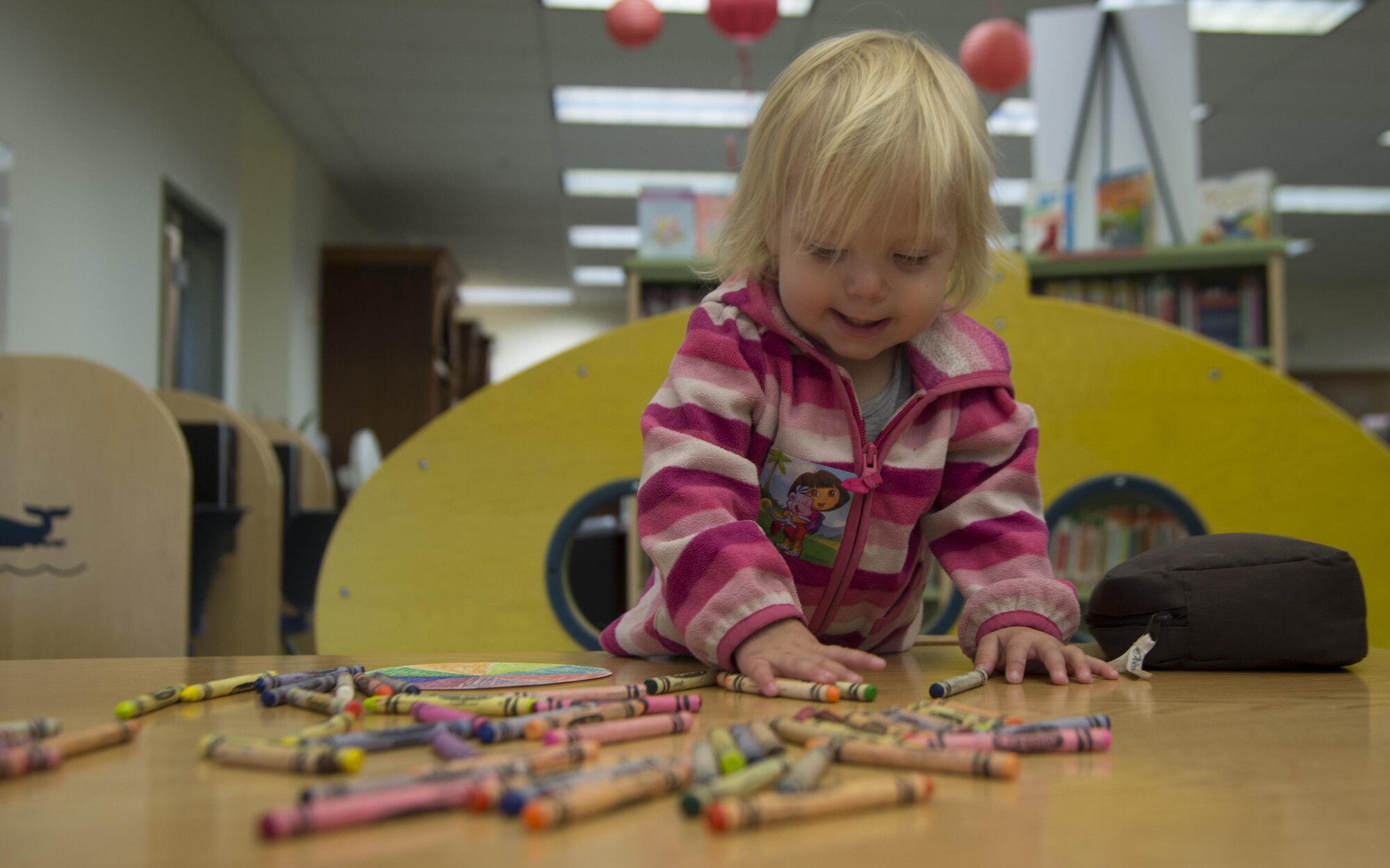 Anastasia, 1, plays with crayons after the preschool story time offered at Joint Base Elmendorf-Richardson, Alaska, Sept. 8, 2016. Story time programs introduce young children to books, rhymes, music and other fun activities. 