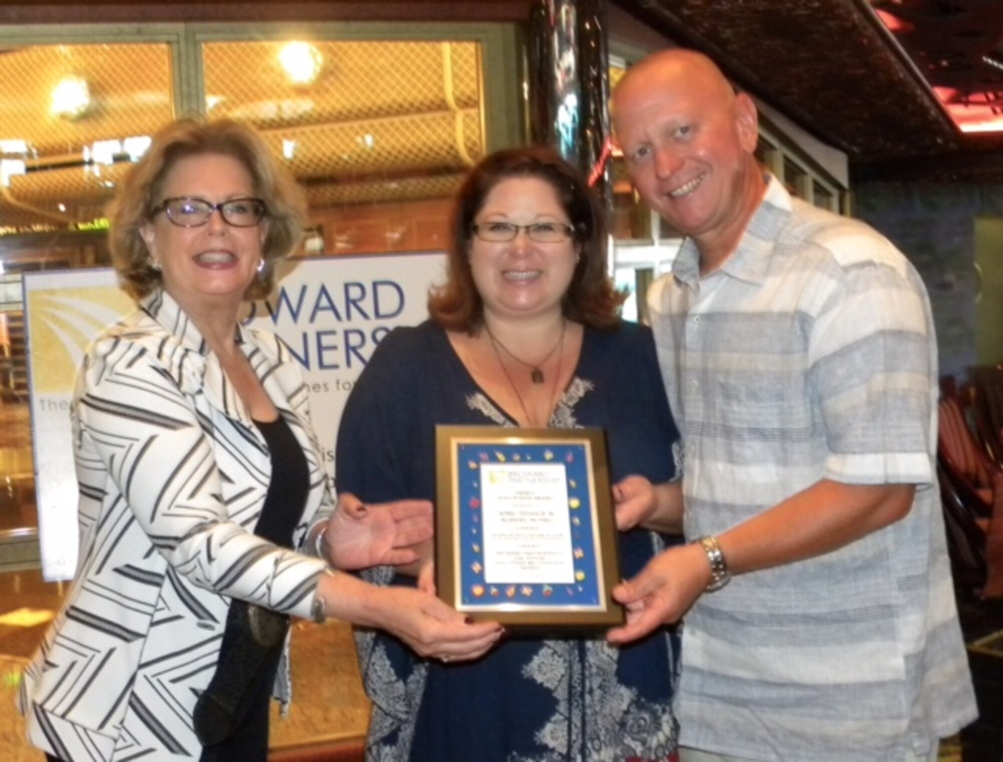 DonnaLee Minott, left, the community engagement manager for the Broward Partnership, presents Staff Sgt. Robert Munro, a 482nd Medical Squadron medical technician, and his wife, April Teddlie, with the 2016 Family Volunteer of the Year Award on board a cruise ship at Port Everglades, Florida, July 16 2016. (Courtesy photo)