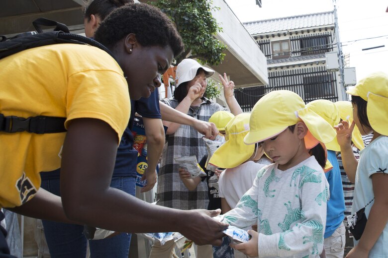 U.S. Navy Chief Petty Officer select Lamonica Harrison, chief hospital corpsman select with the Branch Health Clinic on Marine Corps Air Station Iwakuni, hands juice to a local Japanese child at Ekimae Hoikuen preschool in Iwakuni, Japan, Sept. 8, 2016. After completing the maintenance at the school, the Seabees provided drinks and chips to the students and had the opportunity to talk with them about the maintenance they completed. (U.S. Marine Corps photo by Lance Cpl. Joseph Abrego)