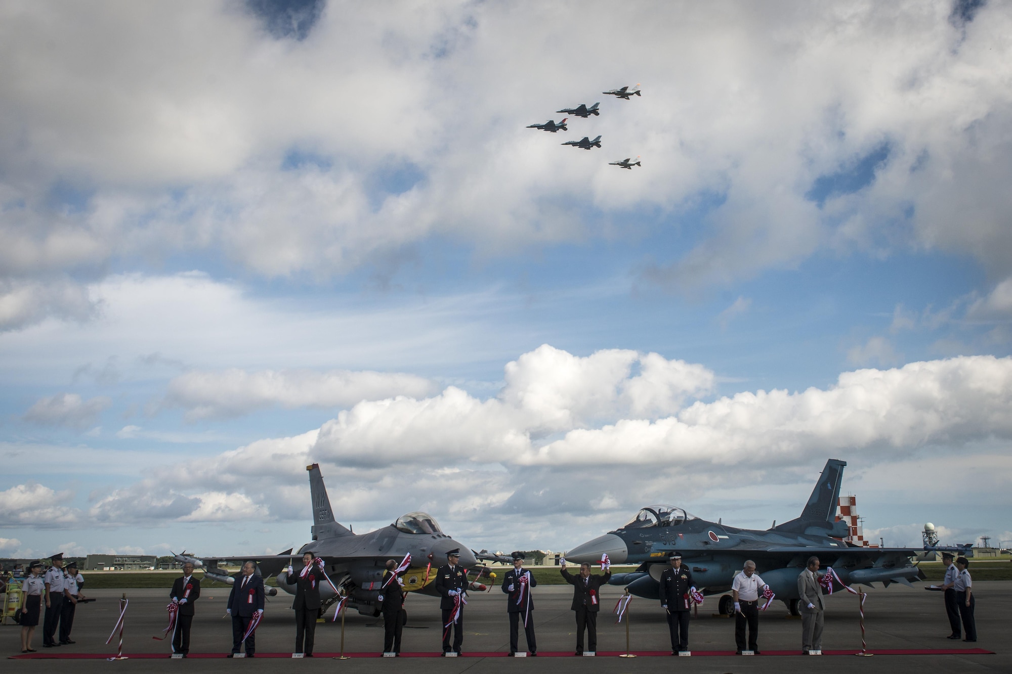 Japanese Air Self-Defense Force and Misawa City officials with U.S. Air Force Col. R. Scott Jobe, the 35th Fighter Wing commander, cut the ribbon as a five-jet formation flies over during Misawa Air Fest 2016’s opening ceremony at Misawa Air Base, Japan, Sept. 11, 2016. The 35th Fighter Wing’s F-16 Fighting Falcon and JASDF 3rd Air Wing’s F-2 serve as a backdrop during the ceremony. More than 80,000 people from Aomori Prefecture and as far as Akita Prefecture attended the annual air show, highlighting the close U.S. and Japan bilateral partnership in the area. (U.S. Air Force photo by Staff Sgt. Benjamin W. Stratton)