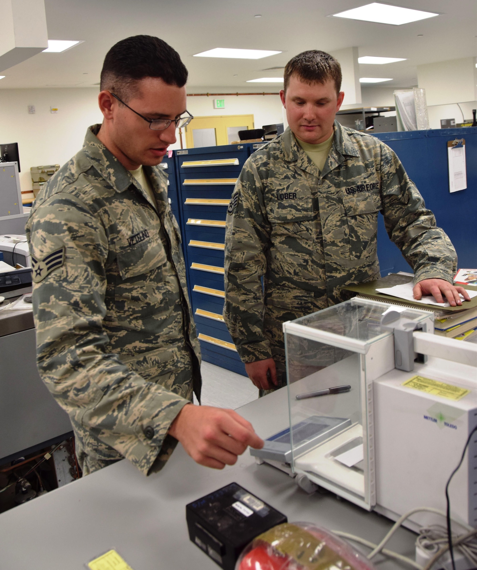 Senior Airmen Eric Vetelino(left) and Staff Sgt. Jacob Lober(right),  379th Expeditionary Expeditionary Maintenance Squadron Precision Measurement Equipment Laboratory craftsmen,  check analytical balance during a calibration test Aug. 24, 2016, Al Udeid Air Base, Qatar.  The 379th EMS PMEL shop supports the calibration of 13,700 pieces of equipment assigned to over 300 work centers at 24 bases in 10 countries in the Central Command area of responsibiity. (U.S. Air Force photo/Technical Sgt. Carlos J. Treviño/Released)