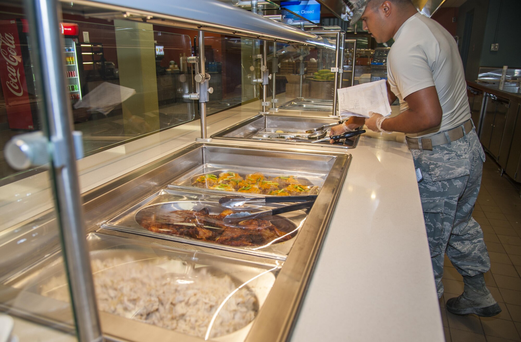 A 5th Force Support Squadron Airman prepares his food line before lunch starts at Minot Air Force Base, N.D., Sept. 7, 2016. The Dakota Inn Dining Facility menu items rotate every day for four weeks so that Airmen have a variety to choose from. (U.S. Air Force photo/Airman 1st Class Christian Sullivan)