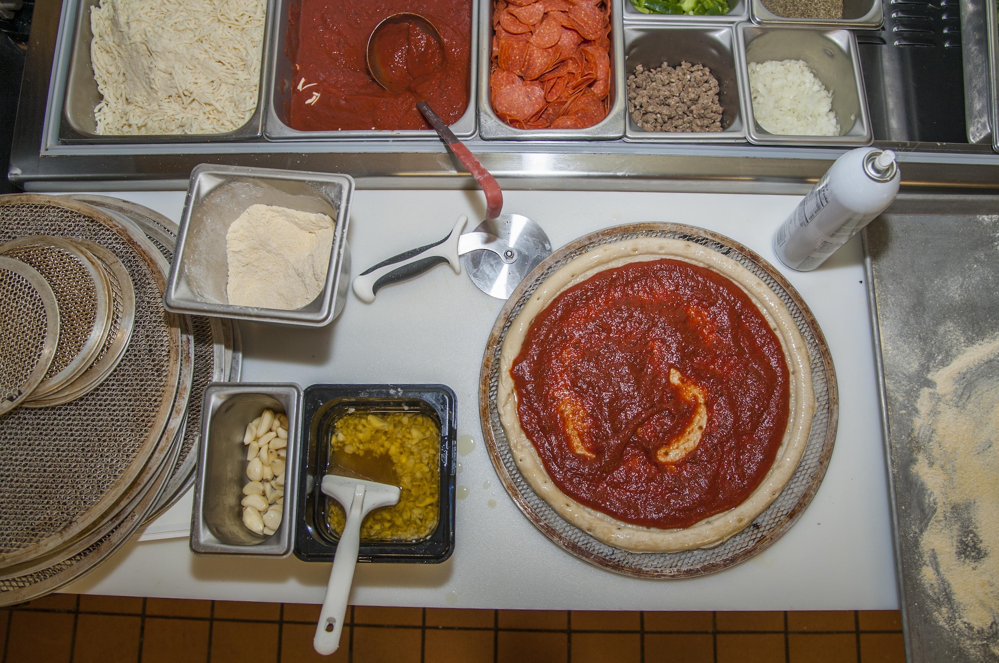 A pizza is prepared before lunch at Minot Air Force Base, N.D., Sept. 7, 2016. The dining facility cooks about 12 pizzas every day for lunch guests. (U.S. Air Force photo/Airman 1st Class Christian Sullivan)