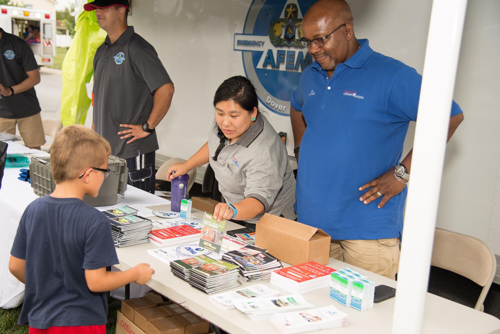 The Delaware Emergency Management Agency Citizen Corps Program managers hand out emergency preparedness books during the Emergency Management Block Party Sept. 1, 2016, on base housing at Dover Air Force Base, Del. The Citizen Corp Program develops community action plans, assesses possible threats and identifies local resources during emergency situations. (U.S. Air Force photo by Mauricio Campino)