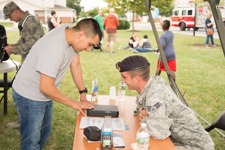 An attendee at the Emergency Management Block Party receives information on proper weapons storage Sept. 1, 2016, in the Eagle Heights family housing on Dover Air Force Base, Del. The block party included fire truck tours, military working dog demonstrations, informational booth games and prize giveaways all associated with National Preparedness Month. (U.S. Air Force photo by Mauricio Campino)