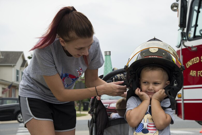 Liam Weeks, 3, son of Staff Sgt. Jesse Weeks, 436th Operations Support Squadron air traffic controller, tries on a firefighter helmet as Kassi Weeks, his mother, assists during the Emergency Management Block Party on Sept. 1, 2016, in base housing on Dover Air Force Base, Del. About 150 members of Team Dover attended this year’s block party. (U.S. Air Force photo by Senior Airman Aaron J. Jenne)