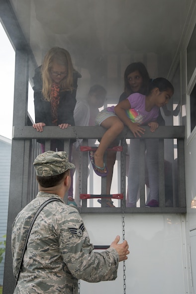 Senior Airman Jamie Perigny, 436th Civil Engineer Squadron firefighter, ensures children safely exit the squadron’s smoke house trailer during the Emergency Management Block Party on Sept. 1, 2016, in base housing on Dover Air Force Base, Del. The trailer simulates the smoky effect produced by a house fire to allow children to practice life-saving techniques in a nonhazardous environment. (U.S. Air Force photo by Senior Airman Aaron J. Jenne)