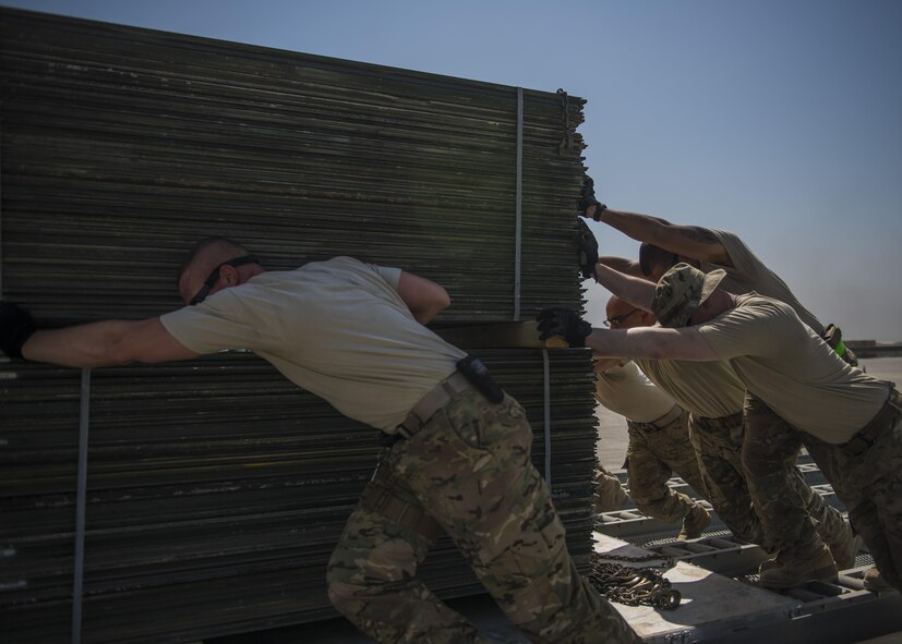 Airmen from the 455th Expeditionary Logistics Squadron Central Command Material Recovery Element, push a load of AM-2 matting onto a pallet, Bagram Airfield, Afghanistan, Sept. 9, 2016. CMRE accounts for and redeploys war reserve assets. The team palletized the matting and transported it to another base. The matting is used to form runways, taxiways, parking and other areas required for aircraft operations and maintenance. (U.S. Air Force photo by Senior Airman Justyn M. Freeman)