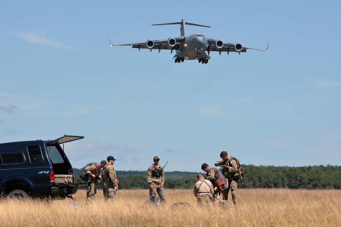 Airmen prepare their equipment as a C-17 Globemaster flies overhead before a training jump over Francis S. Gabreski Air National Guard Base in Westhampton Beach, N.Y., Aug. 31, 2016. Air National Guard photo by Staff Sgt. Christopher S. Muncy