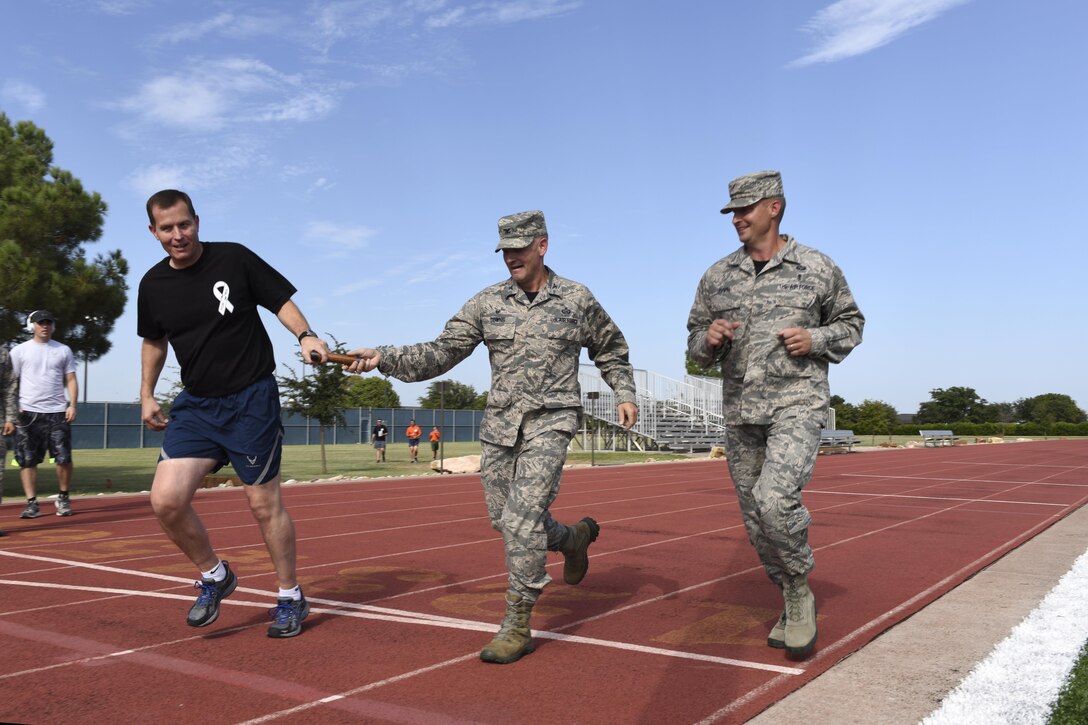 U.S. Air Force Col. Michael Downs, 17th Training Wing Commander, and Chief Master Sgt. Rye Bavin, 17th Medical Group superintendent, pass the baton to Col. Jeffrey Sorrell, 17th Training Wing Vice Commander, during a relay race at the Mathis Fitness Center track on Goodfellow Air Force Base, Texas, Sept. 9, 2016. The relay was part of a POW/MIA 24-hour remembrance run. (U.S. Air Force photo by Airman 1st Class Chase Sousa/Released)
