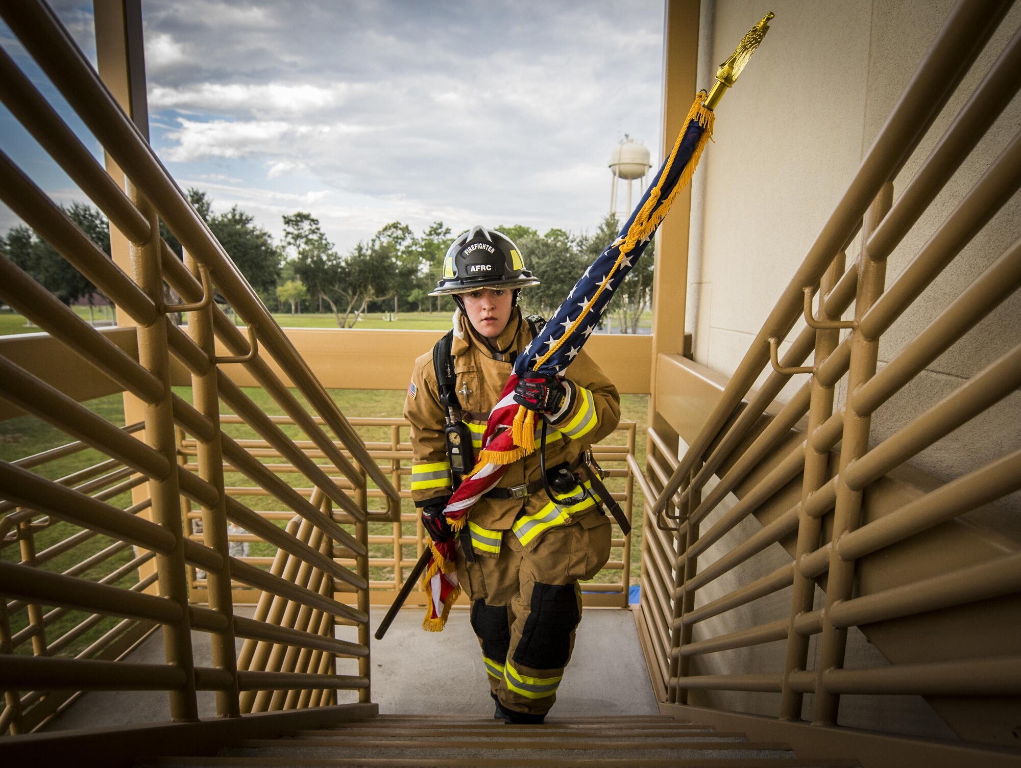 Airman Virginia Davis, 919th Special Operations Civil Engineer Squadron, carries an American flag up a flight of stairs while wearing her firefighting gear during a 9/11 Memorial Stair Climb event at Duke Field, Fla., Sept. 11.  The 24-hour climb began at 8:46 a.m. Sept. 10 with the 919th Special Operations Wing commander walking the flag up the outside stairwell of the base’s billeting facility.  Wing Airmen took turns walking the flag up and down the stairwell the entire day until it was delivered to a firefighter and security forces color guard at 8:46 a.m. the next morning for a 9/11 Remembrance ceremony.  More than 115 Airmen carried the flag throughout the day and night for a total of more than 207,000 steps.  (U.S. Air Force photo/Tech. Sgt. Sam King)