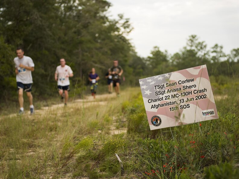 Runners move by a sign displaying the name of fallen Air Force special operator who lost his life after 9/11 during the Memorial 6k trail run Sept. 11 at Duke Field, Fla.  About 100 Airmen and families participated in the run.  (U.S. Air Force photo/Tech. Sgt. Sam King)