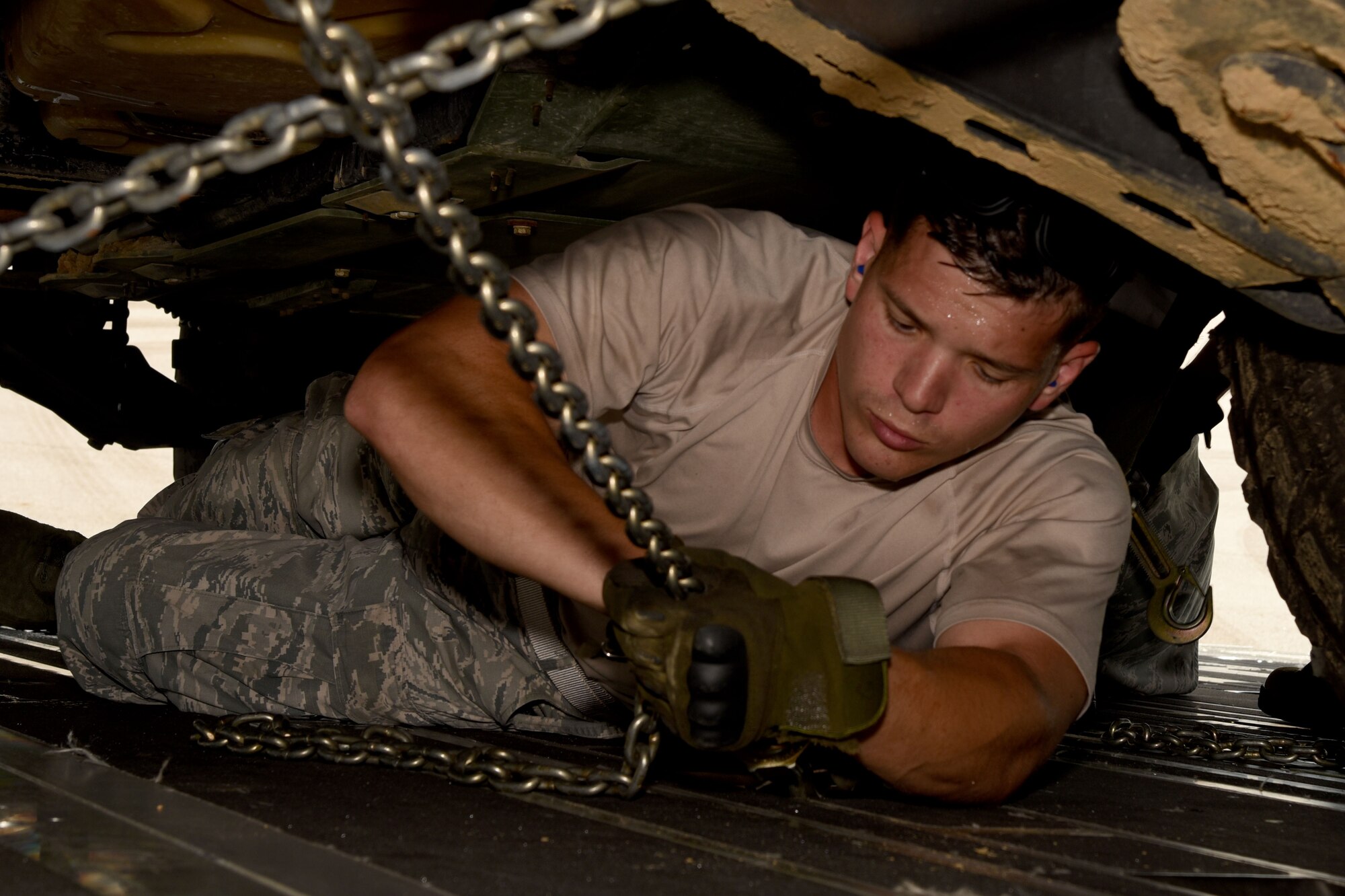Staff Sgt. Anthony Gaston, 41st Aerial Port Squadron air transportation specialist, tightens the chains from underneath a loaded Humvee onboard a C-17 Globemaster III during joint training mission Patriot Mustang GRIP II (Guard Reserve Inspiring Patriots). The mission included members of the Air Force Reserve, Army National Guard and Naval personnel at Stennis Space Center. (U.S. Air Force photo/Staff Sgt. Nicholas Monteleone)
