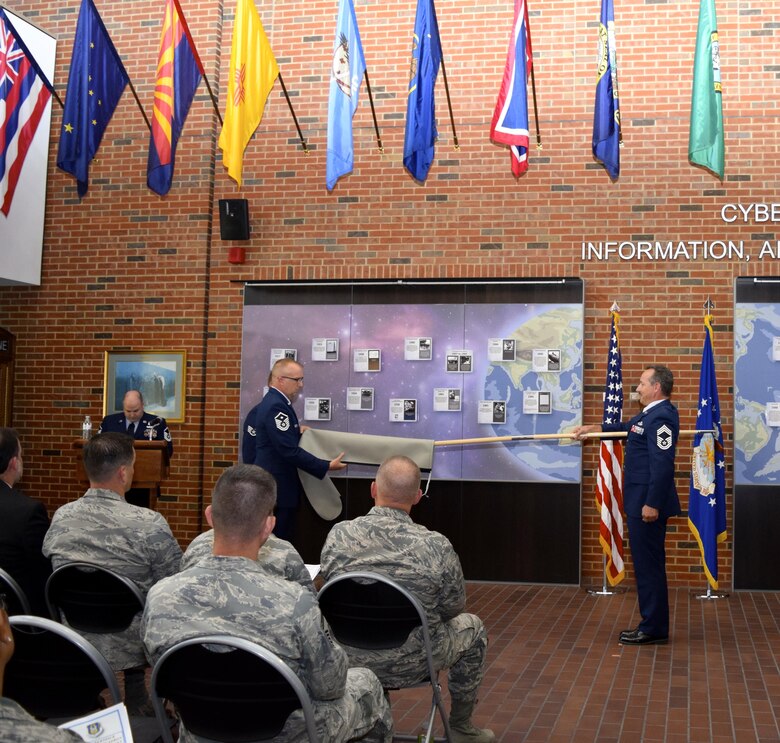 Chief Master Sgt. Mark Otzenberger, the new 42nd Cyberspace Operations Squadron superintendent, holds the squadron guidon as Master Sgt. Jeffery Hall, the 42nd COS first sergeant, removes the case and prepares to unfurl the new flag. The 42nd Cyberspace Operations Group was activated during a ceremony in the Ludwig Heritage Hall Atrium at Scott Air Force Base Sept. 12. (U.S. Air Force photo by Maj. Alysia Harvey)