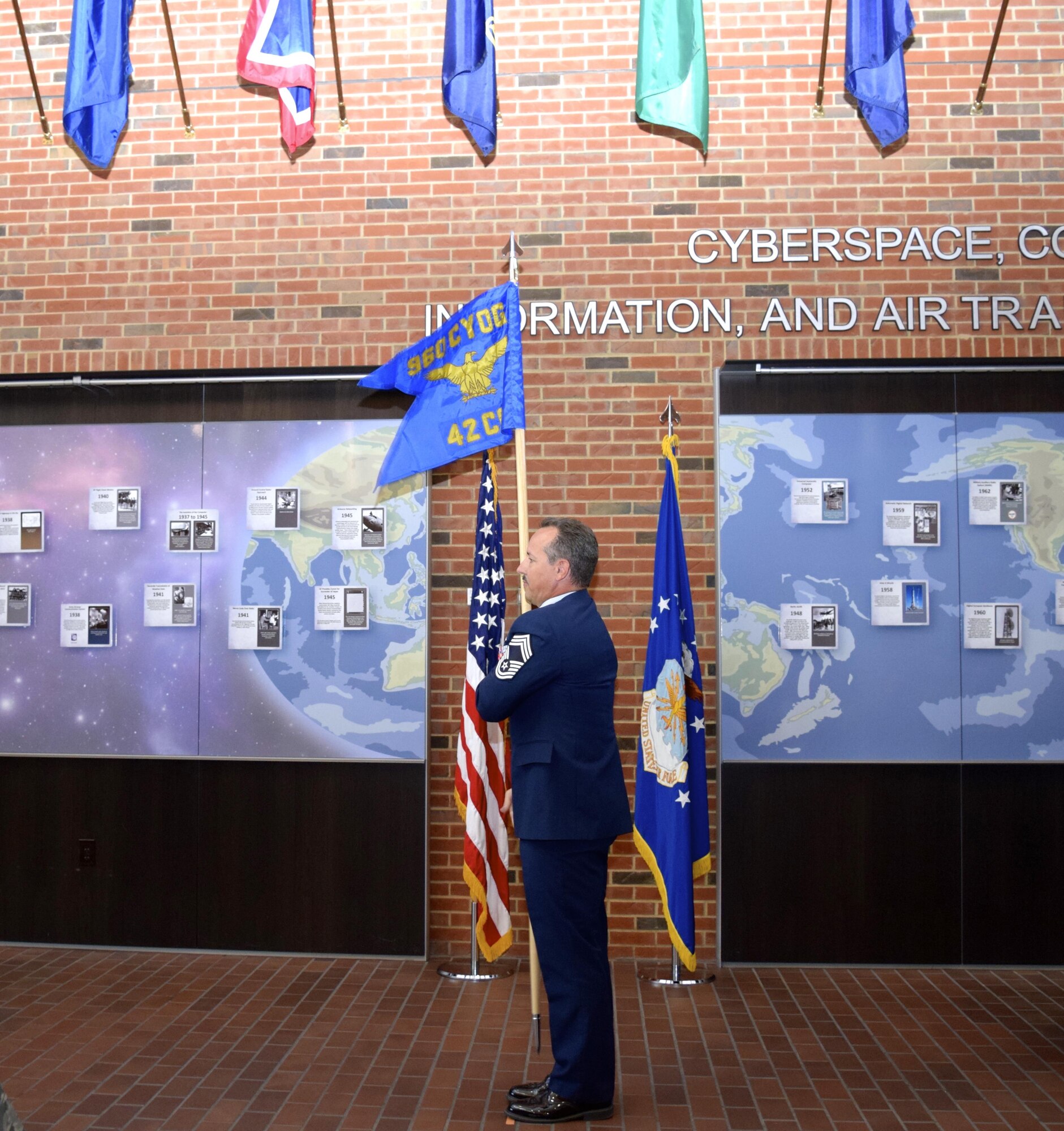 Chief Master Sgt. Mark Otzenberger, the new 42nd Cyberspace Operations Squadron superintendent, holds the new squadron guidon after it was unfurled during a ceremony in the Ludwig Heritage Hall Atrium at Scott Air Force Base Sept. 12. The 42nd COS has a rich history dating back to 1949 when it was first activated at Mitchell Air Force Base, New York. (U.S. Air Force photo by Maj. Alysia Harvey)