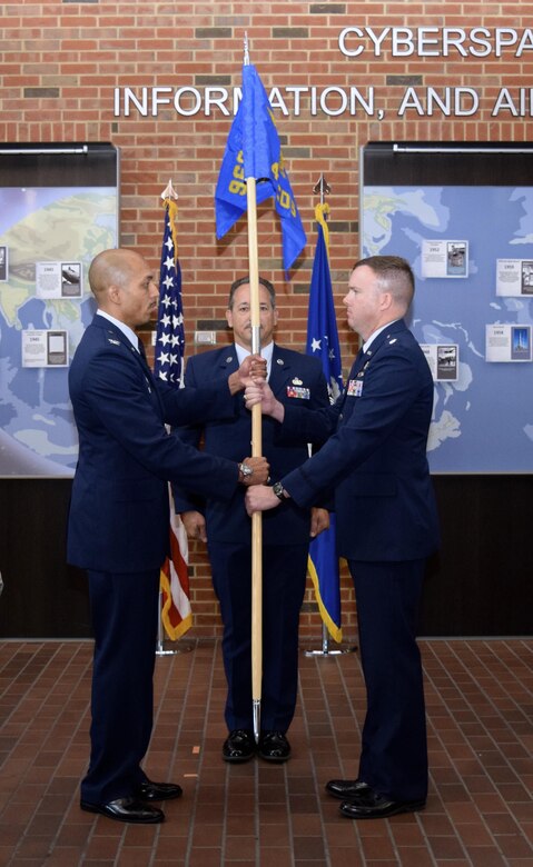 Lt. Col. Samuel McGlynn accepts the 42nd Cyberspace Operations Group guidon, assuming command of the squadron, from Col. Anthony M. Perkins, 960th Cyberspace Operations Group, as Chief Master Sgt. Mark Otzenberger, the squadron's new superintendent looks on, during a ceremony in the Ludwig Heritage Hall Atrium at Scott Air Force Base Sept. 12. The 42nd COS has a rich history, dating back to just after World War II when the 42nd Communications Squadron was first activated at Mitchell Air Force Base, New York, Nov. 17, 1949. (U.S. Air Force photo by Maj. Alysia R. Harvey)
