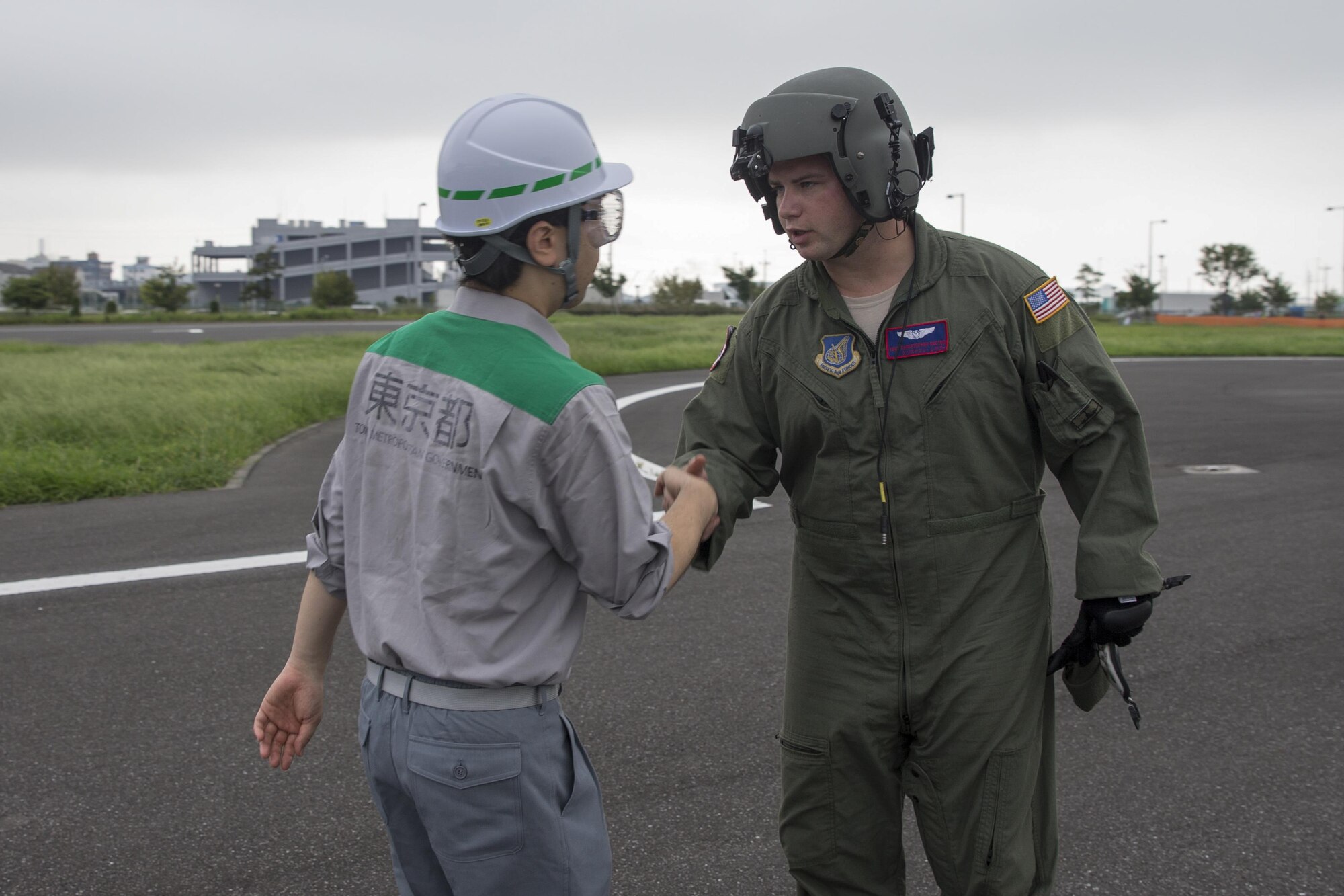 Tech. Sgt. Christopher Rector, 459th Airlift Squadron flight engineer, greets to a member with the Tokyo Metropolitan Government after landing the Tokyo Rinkai Disaster Prevention Park, Japan, Sept. 4, 2016, during the Annual Tokyo Metropolitan Government Disaster Management Drill. Airmen with the 459 AS practiced delivering simulated relief supplies to Tokyo Rinkai Disaster Prevention Park in downtown Tokyo. The park is located in the Ariake area and is a disaster countermeasure headquarters of the Government of Japan and other local governments during large-scale earthquakes in the metropolitan area. (U.S. Air Force photo by Yasuo Osakabe/Released)    