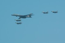 A U.S. Air Force B-1B Lancer, escorted by U.S. Air Force F-16 Fighting Falcons, performs a flyover over Osan Air Base, ROK, Sept. 13, 2016. The flyover highlighted the close cooperation between American and ROK military forces that keeps them ready to respond at any time to threats to stability and security. The B-1s are currently assigned to Andersen Air Force Base, Guam. (U.S. Air Force photo by Senior Airman Dillian Bamman) )