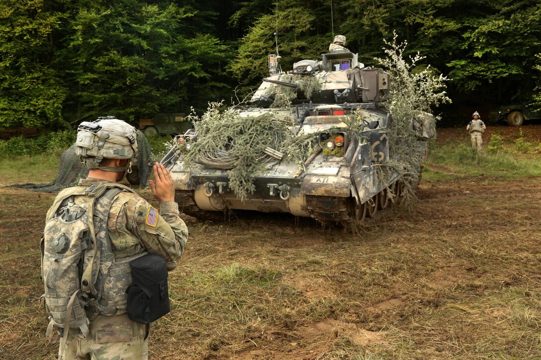 Soldiers ground guide an M2 Bradley fighting vehicle into a tree line while conducting a defensive scenario during exercise Combined Resolve VII at Hohenfels, Germany, Sept. 4, 2016. The soldiers are assigned to the 2nd Battalion, 7th Infantry Regiment, 1st Armored Brigade. U.S. Army photo by Pfc. Caleb Foreman
