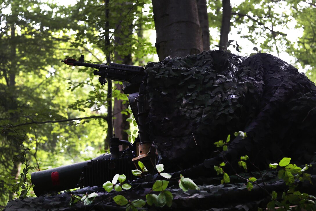 A soldier tends to his machine gun under camouflage while conducting security operations during exercise Combined Resolve VII at Hohenfels, Germany, Sept. 4, 2016. Army photo by Spc. Gage Hull