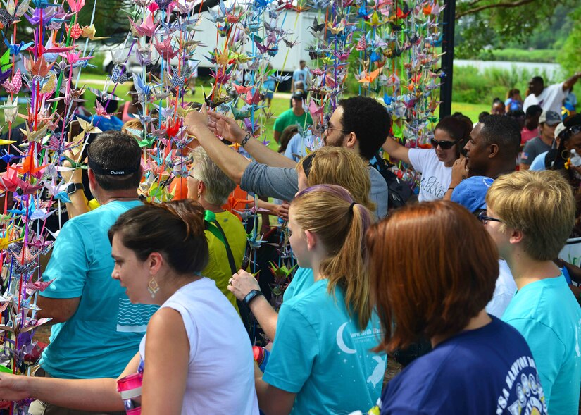 Participants walk through the 1,000 crane curtain during the Out of the Darkness Community Walk at Mount Trashmore Park, Virginia Beach, Va., Sept. 10, 2016. The crane was chosen to represent the Out of the Darkness community walk as it, over the centuries, has become a symbol of healing, happiness and hope. In Japan people believed this ancient bird lived for a 1,000 years. Legend has it that, if you fold 1000 paper cranes, your prayers will be answered. Volunteers of the Walk have folded this many with our prayers for peace, not only for those who presently suffer from depression but also for those who have died by suicide. (U.S. Air Force photo by Tech. Sgt. Daylena S. Ricks)