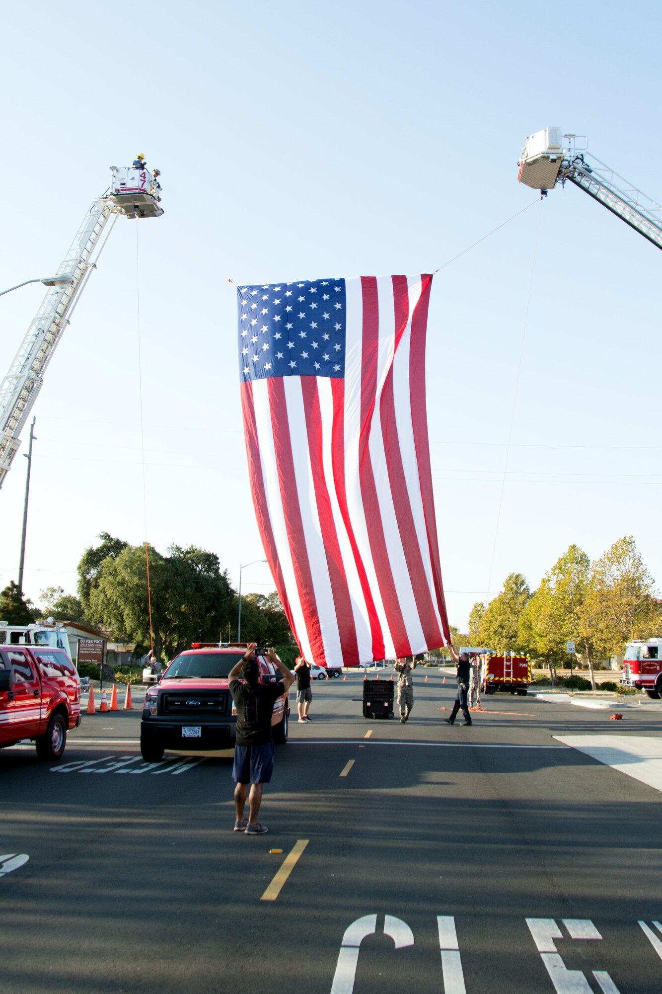 Firefighters from the 60th and 349th Civil Engineer Squadrons and the Suisun City Fire Department hang a flag between two firetrucks before the Run for the Fallen event on Sept. 10, 2016 at Travis Air Force Base, Calif. The run was held to honor the 343 firefighters who lost their lives on Sept. 11, 2001. (U.S. Air Force photo by Senior Airman Shelby R. Horn/Released)