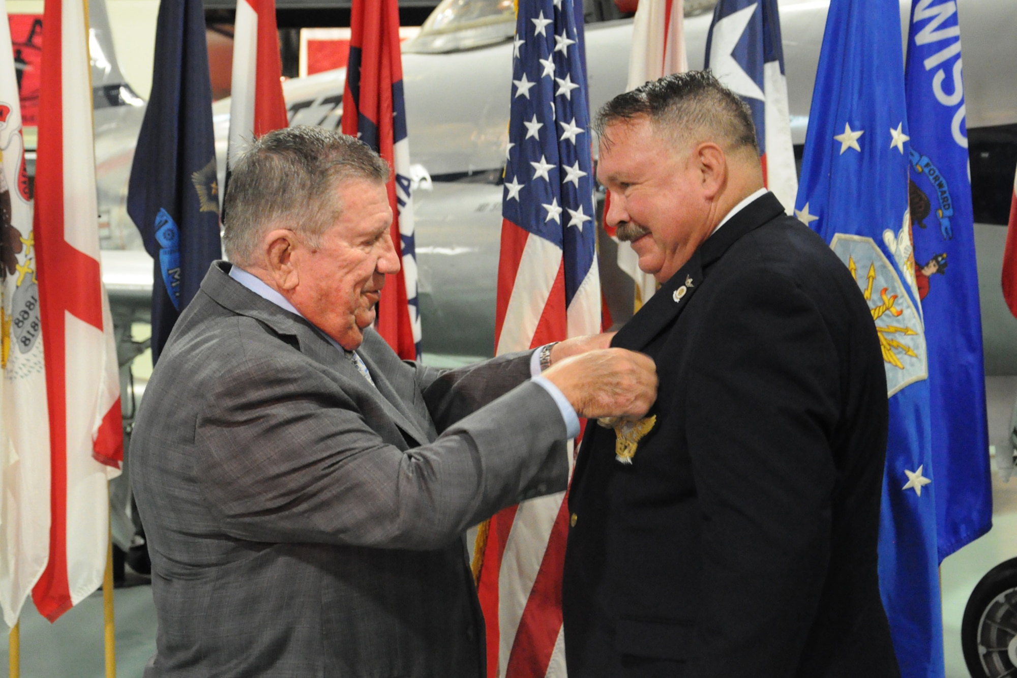 Retired Maj. Gen. Richard Secord places the retirement pin on Dr. Charles “Doc” Merkel during a ceremony Aug. 30, at the Air Force Armament Museum on Eglin Air Force Base, Fla. Merkel served at the 53rd Wing historian from 2007 to 2016.