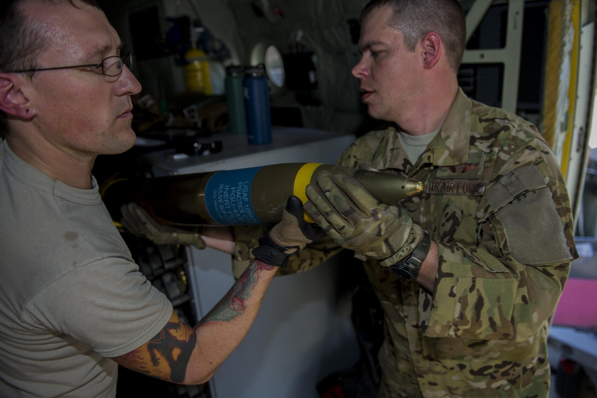 Tech. Sgt. Johnny Hooker, an aerial gunner with the 1st Special Operations Group Detachment 2, hands a 105 mm round to Staff Sgt. Derek Watson, an aerial gunner with 1 SOG Det. 2, for inspection during a weapons load at Hurlburt Field, Fla., Sept. 6, 2016. Each handler inspects the overall condition of the round before it is loaded. (U.S. Air Force photo by Airman 1st Class Isaac O. Guest IV)