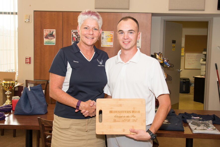 Dawne Nickerson-Banez, 436th Public Affairs community relations chief, presents a trophy to Senior Airman Zachary Zilch, 436th Logistics Readiness Squadron fuels distribution operator, during the 2016 fall Bluesuiters Golf Tournament Sept. 9, 2016, at the Eagle Creek Golf Course on Dover Air Force Base, Del. Zilch was a sponsored participant of the tournament that is aimed at maintaining good community relations with Team Dover Airmen. (U.S. Air Force photo by Mauricio Campino)