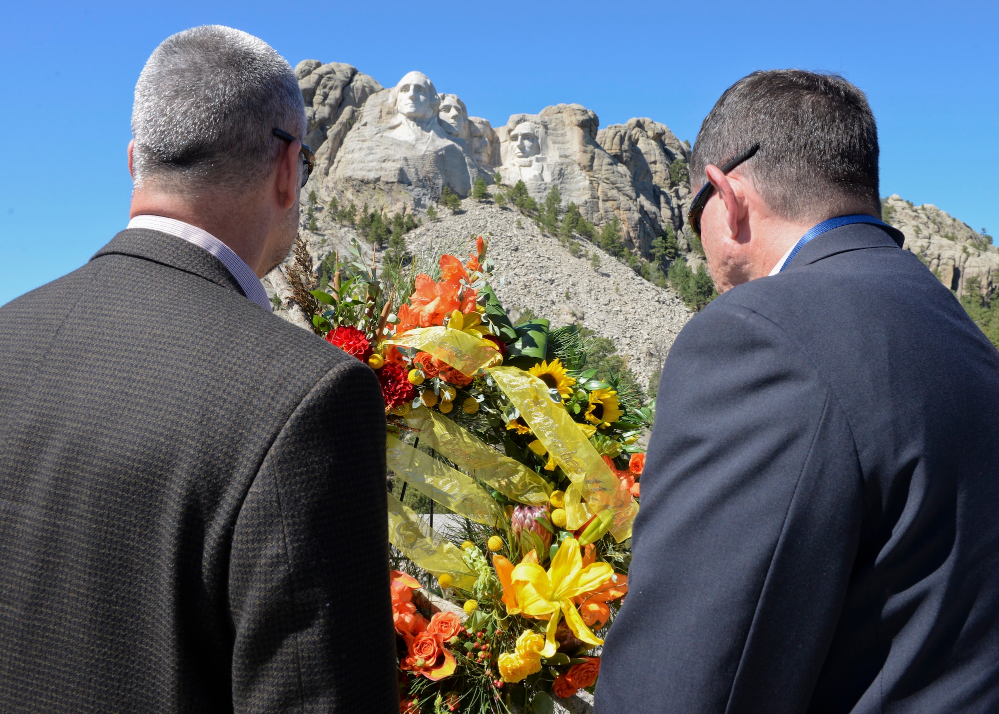 Rear Admiral William Truelove, Canadian Navy, and John A. Atela, director of the Office of Partner Engagement, stand in silence at the Mount Rushmore National Memorial, S.D., Sept. 11, 2016, to honor the 15th anniversary of the attacks on Sept. 11, 2001. A wreath laying ceremony was conducted by senior foreign and U.S. attachés on behalf of the Foreign Defense Attaché Corps, an organization based in Washington D.C., and made up of more than 120 nations. (U.S. Air Force photo by Senior Airman Anania Tekurio)