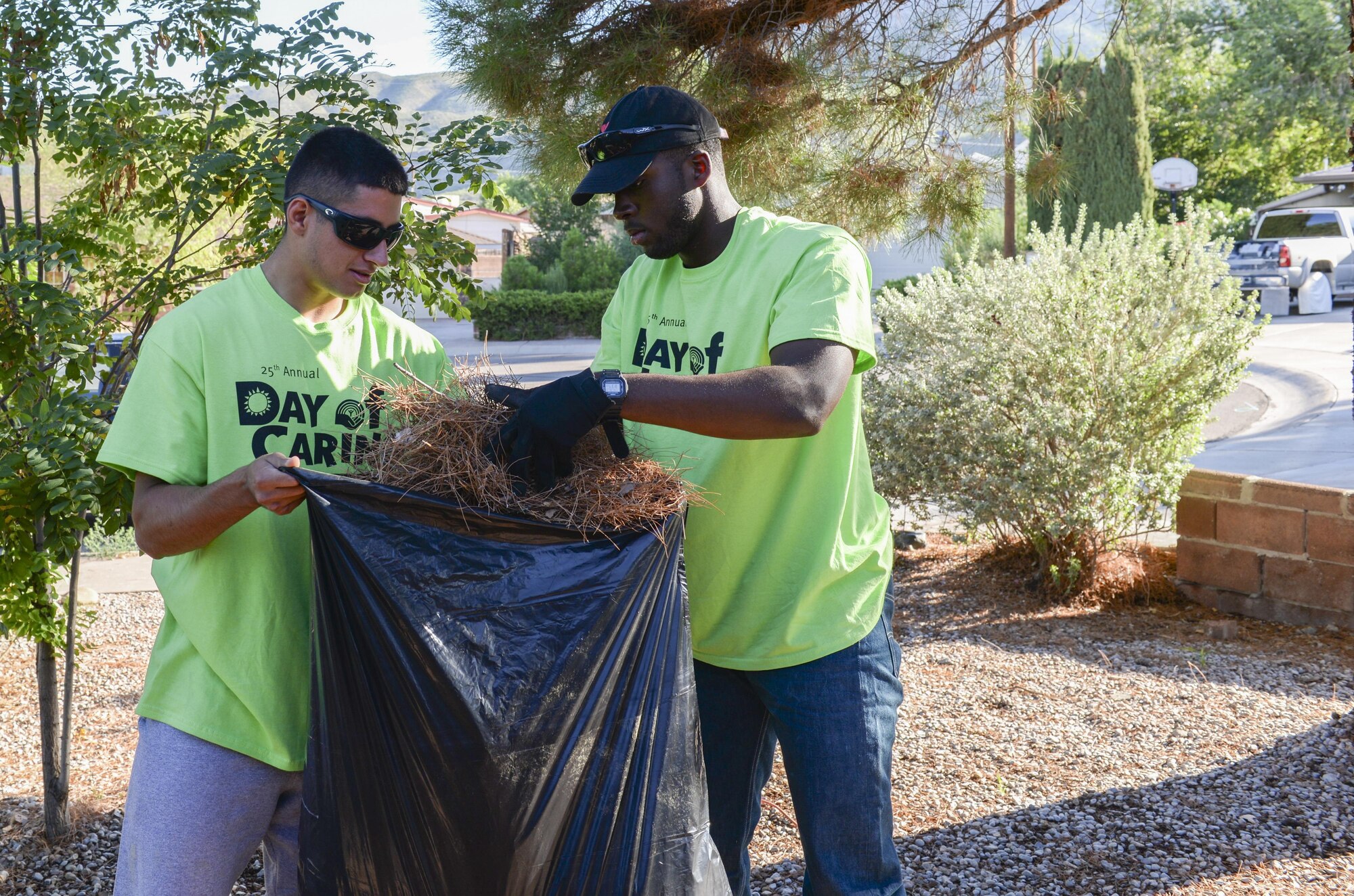 Airmen 1st Class Michael and Michael, Day of Caring volunteers, who are both heating, ventilation and air conditioning technicians with the 49th Civil Engineer Squadron here, gather pine needles from a disabled resident’s front lawn in Alamogordo, N.M. on Sept. 9, 2016. The annual Day of Caring volunteer event helps disabled individuals and senior citizens within the Otero County community. (Last names are being withheld due to operational requirements. U.S. Air Force photo by Airman Alexis P. Docherty)