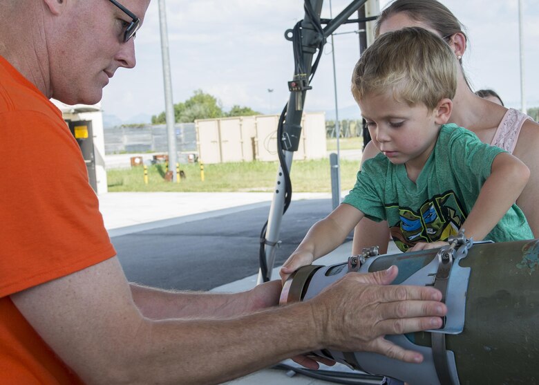 Maj. Joseph Pulliam, 31st Munitions Squadron commander, and Riley Gould, son of Staff Sgt. Derek Gould, 31st MUNS munitions inspector, build a mock munition during a family open house event at Aviano Air Base, Italy on Sept. 9, 2016. Spouses and children of 31st MUNS Airmen spent the day touring squadron facilities and participating in on-the-job activities to better understand what their Airmen do on a daily basis. (U.S. Air Force photo by Airman 1st Class Cory W. Bush/Released)
