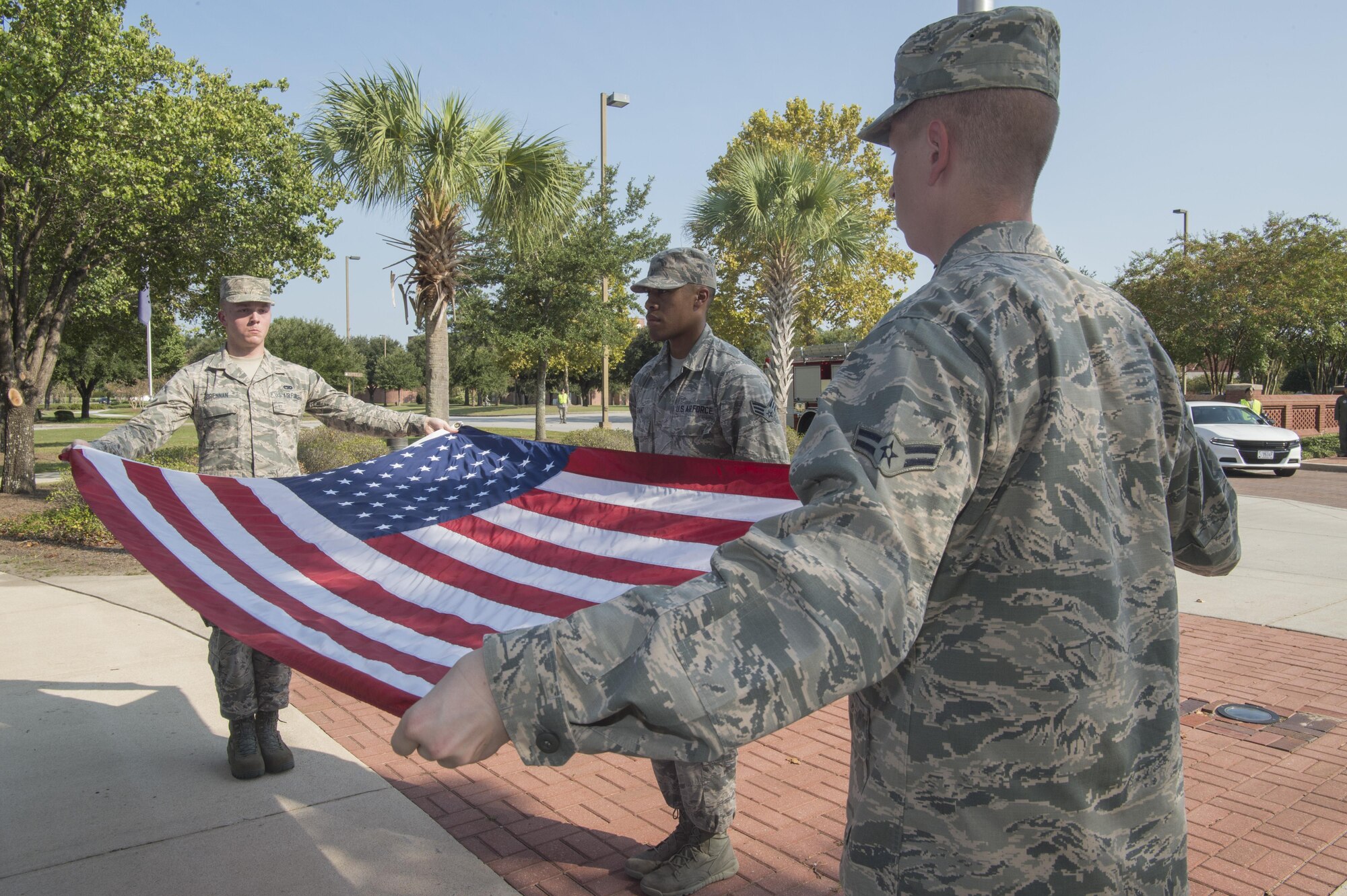 (From left to right) Joint Base Charleston Honor Guard members Airman 1st Class Court Brennan, Senior Airman Cornelius Grant and Airman 1st Class Alexander Klimek begin folding the United States flag during the Patriot Day retreat ceremony at Joint Base Charleston, South Carolina, Sept. 9, 2016. Patriot Day is a day of remembrance for those who lost their lives in the terrorist attacks on Sept. 11, 2001. 