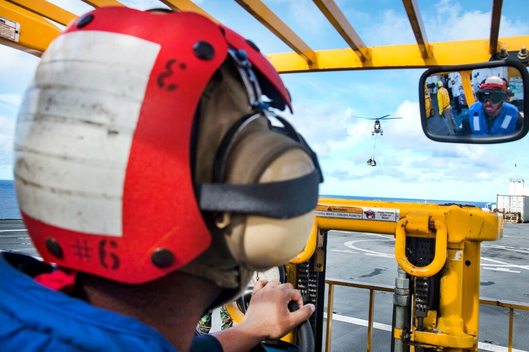 Navy Petty Officer 2nd Class Darrell Reed prepares to pick up supplies being dropped by an SA-330J Puma helicopter during a vertical replenishment in the Pacific Ocean, Sept. 10, 2016. Reed is a logistics specialist. Navy photo by Petty Officer 3rd Class Trevor Kohlrus