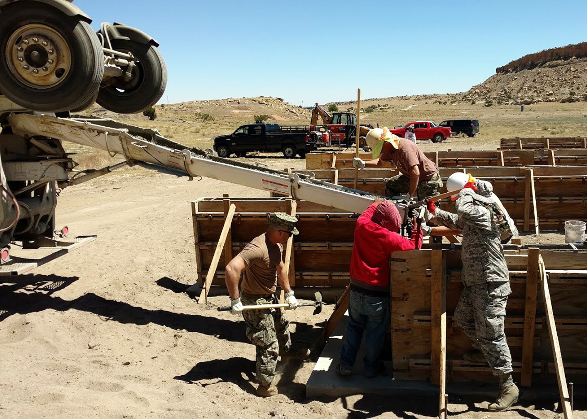 944th Civil Engineering Squadron Airmen and Navy servicemen work together to distribute cement into stem wall forms Jul 18 during Operation Footprint in Gallup, NM. (Courtesy photo)