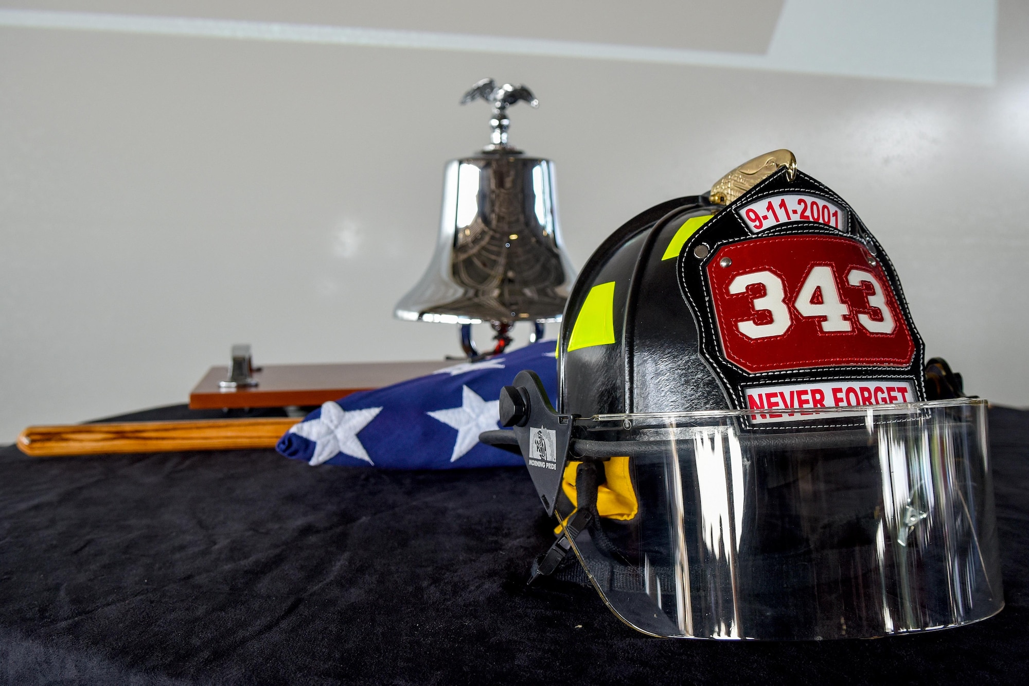 A helmet and bell are front and center at a 9/11 Remembrance ceremony, Sept. 11, 2016, at Seymour Johnson Air Force Base, North Carolina. The helmet bears the date of 9/11 and the number 343, representing the number of first responders who perished at Ground Zero. (U.S. Air Force photo by Airman Shawna L. Keyes)