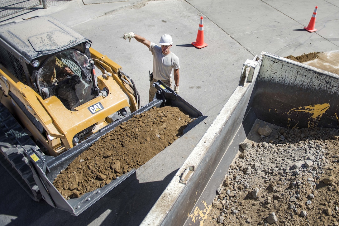 Air Force Staff Sgt. Casey Epps, right, provides directions to Air Force Senior Airman Bobby Rayscales Jr. as he unloads dirt during the construction of a new drainage system at Bagram Airfield, Afghanistan, Sept. 7, 2016. Epps is a pavements and equipment technician and Rayscales is an engineer assistant assigned to the 455th Expeditionary Civil Engineer Squadron. Air Force photo by Senior Airman Justyn M. Freeman 