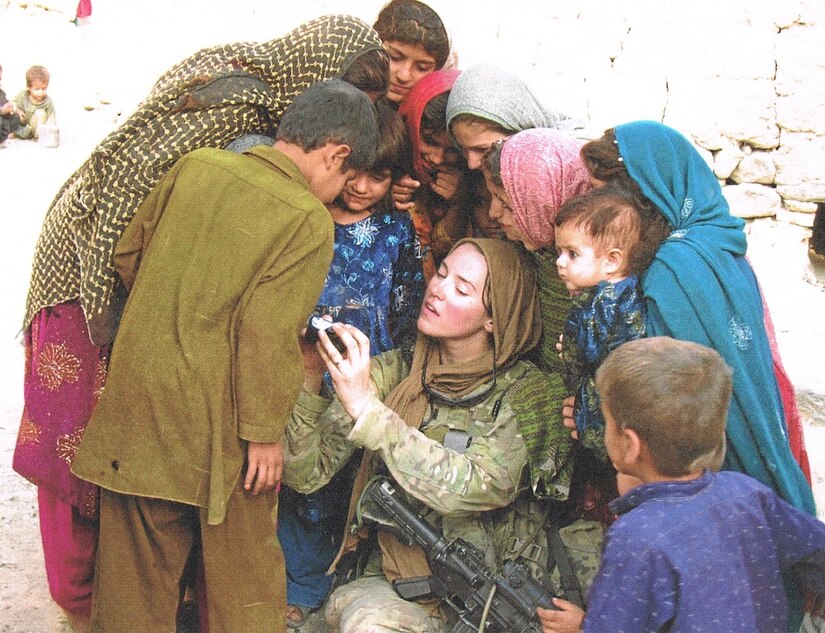 Capt. Laura Starin shows a digital photograph to Afghani children in Sangar Valley, Lagham Province, in Afghanistan in 2011. It is the first digital camera these children had ever seen. Photo by Brad Hahn.