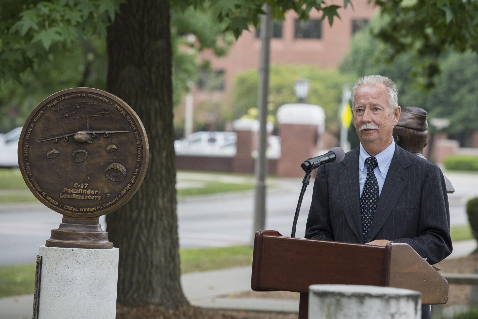 Retired Air Force Cheif Master Sgt. James Lis speaks at a bust dedication honoring the C-17A Pathfinder Loadmasters at Scott Air Force Base, Ill. Sept. 8, 2016. Lis and five others made up the C-17A Pathfinder loadmasters who were being recognized for their efforts in providing the leadership and expertise necessary to guide Mcdonnell Douglas and Military Airlift Command to produce the C-17 Globemaster III. (U.S. Force Photo by Airman Daniel Garcia)
