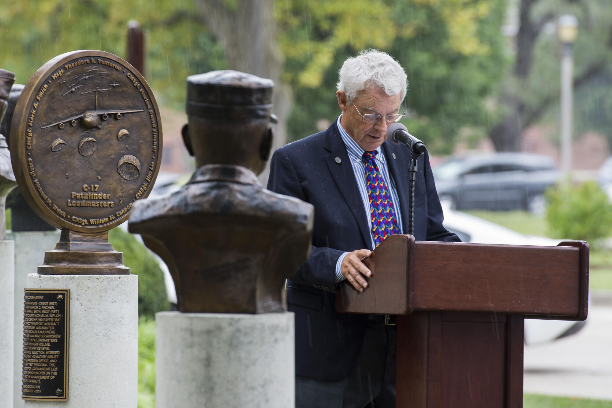 Retired Air Force Cheif Master Sgt. Mike Welch speaks at a bust dedication honoring the C-17A Pathfinder Loadmasters at Scott Air Force Base, Ill. Sept. 8, 2016.  Welch and five others made up the C-17A Pathfinder loadmasters who were being recognized for their efforts in providing the leadership and expertise necessary to guide Mcdonnell Douglas and Military Airlift Command to produce the C-17 Globemaster III. (U.S. Force Photo by Airman Daniel Garcia)