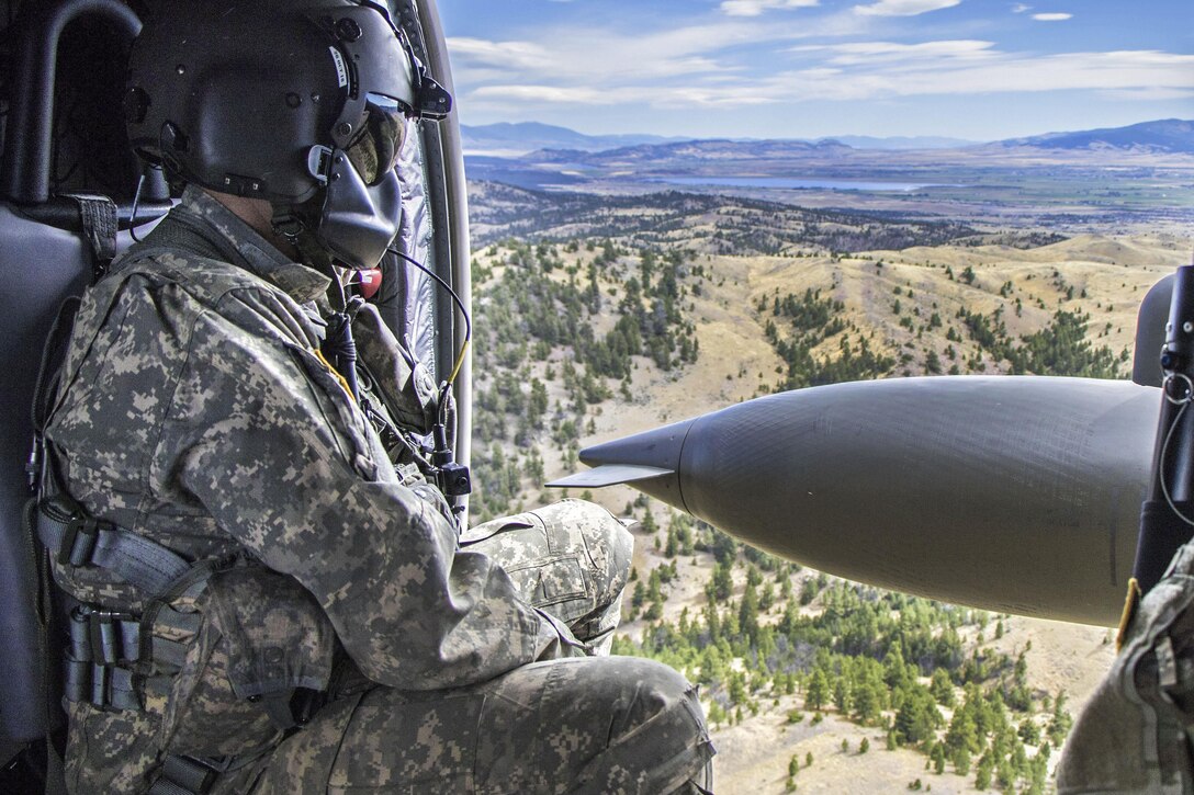 A soldier watches out the side door of a UH-60M Black Hawk helicopter as it flies toward Helena, Mont., Sept. 10, 2016. The soldier is a crew chief assigned to the Montana Army National Guard's 1st Battalion, 189th Aviation Regiment. Army photo by Pfc. Michael Hunnisett