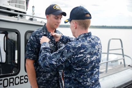 Aviation Boatswain's Mate (Fuels) Second Class Curtis Clausen receives the Navy Small Craft Insignia from Capt Robert Hudson, Deputy Joint Base Charleston commander, at an awards ceremony September 1. Claussen is assigned to a Harbor Patrol Unit (HPU) boat embedded in 628th Security Forces Squadron at Joint Base Charleston.
