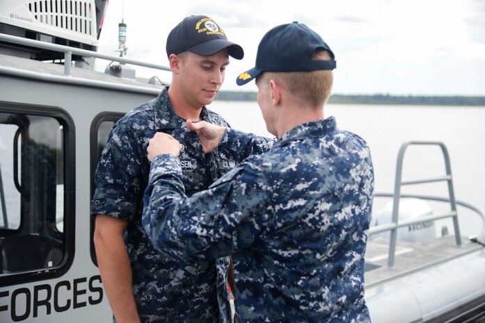 Aviation Boatswain's Mate (Fuels) Second Class Curtis Clausen receives the Navy Small Craft Insignia from Capt Robert Hudson, Deputy Joint Base Charleston commander, at an awards ceremony September 1. Claussen is assigned to a Harbor Patrol Unit (HPU) boat embedded in 628th Security Forces Squadron at Joint Base Charleston.