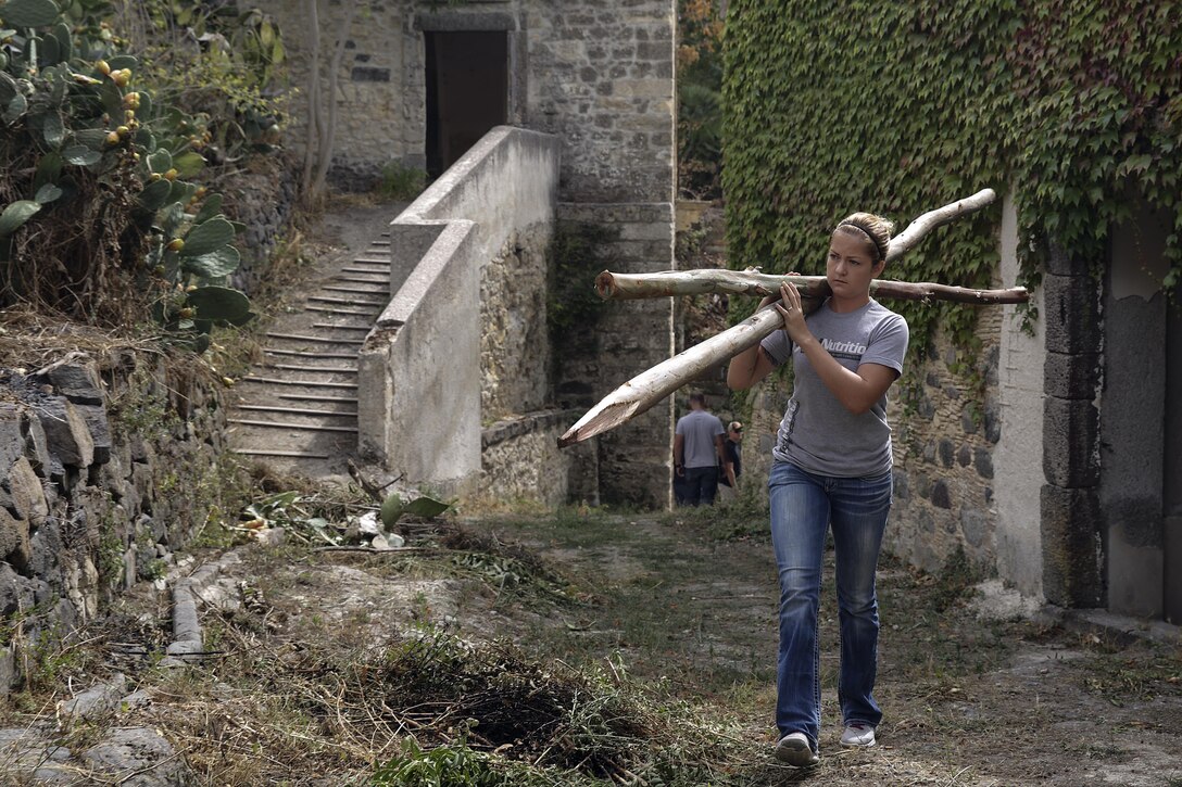 Cpl. Jessica Lucy, a combat engineer with Special Purpose Marine Air-Ground Task Force Crisis Response-Africa, carries fence posts up a hill in Vizzini, Sicily, Sept. 7, 2016.  Marines volunteered to clean up a local historic site and build fences during a community relations project.  (U.S. Marine Corps photo by Cpl. Alexander Mitchell/released)