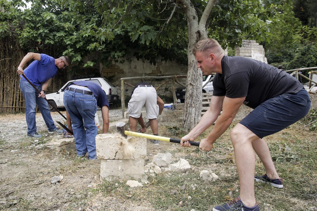 Lance Cpl. Chuck Lacosta, a basic landing support specialist with Special Purpose Marine Air-Ground Task Force Crisis Response-Africa, breaks a cinder block with a sledgehammer in Vizzini, Sicily, Sept. 7, 2016.  Marines volunteered to clean up a local historic site and build fences during a community relations project.  (U.S. Marine Corps photo by Cpl. Alexander Mitchell/released)