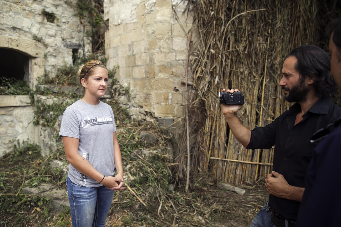 Cpl. Jessica Lucy, a combat engineer with Special Purpose Marine Air-Ground Task Force Crisis Response-Africa, answers a question during an interview about the community relations project in Vizzini, Sicily, Sept. 7, 2016.  Marines volunteered to clean up a local historic site and build fences during a community relations project.  (U.S. Marine Corps photo by Cpl. Alexander Mitchell/released)