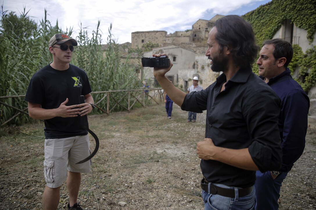 Cpl. Adam Crose, a generator mechanic with Special Purpose Marine Air-Ground Task Force Crisis Response-Africa, answers a question during an interview about the community relations project in Vizzini, Sicily, Sept. 7, 2016.  Marines volunteered to clean up a local historic site and build fences during a community relations project.  (U.S. Marine Corps photo by Cpl. Alexander Mitchell/released)