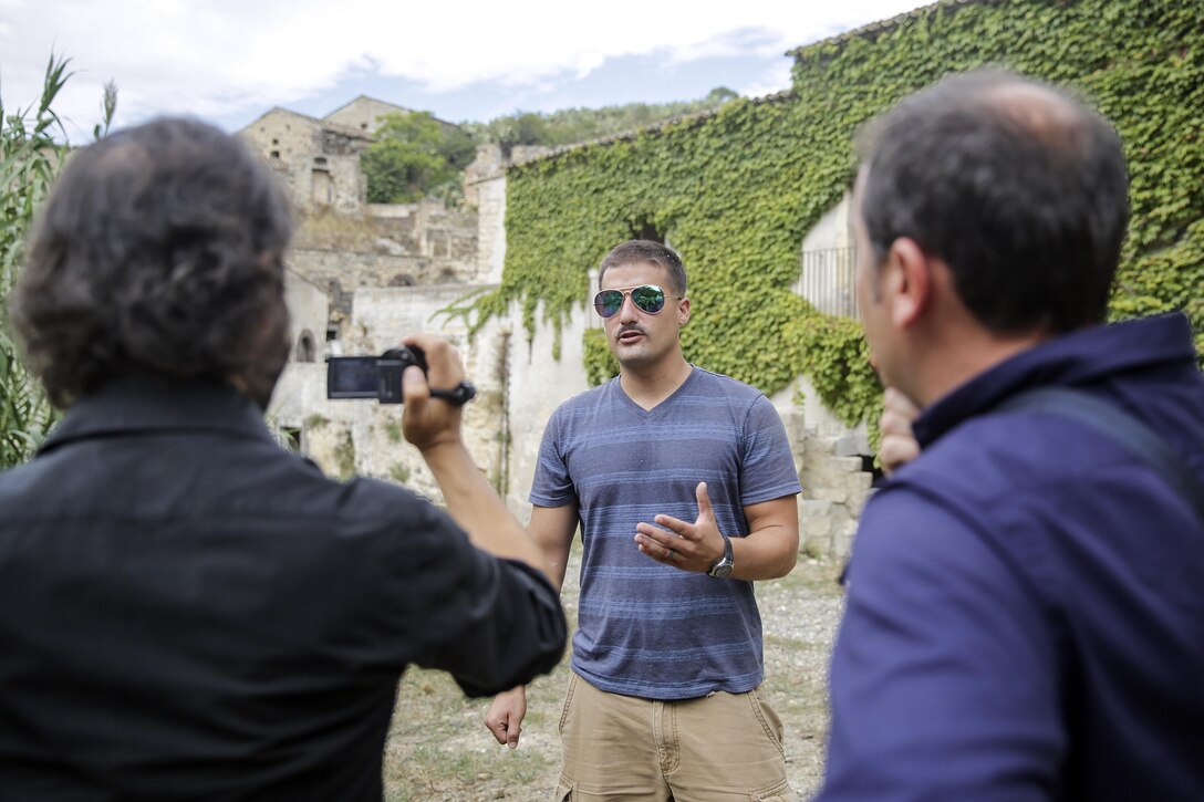 Cpl. Ray Jimenez, a water purification specialist with Special Purpose Marine Air-Ground Task Force Crisis Response-Africa, answers a question during an interview about the community relations project in Vizzini, Sicily, Sept. 7, 2016.  Marines volunteered to clean up a local historic site and build fences during a community relations project.  (U.S. Marine Corps photo by Cpl. Alexander Mitchell/released)