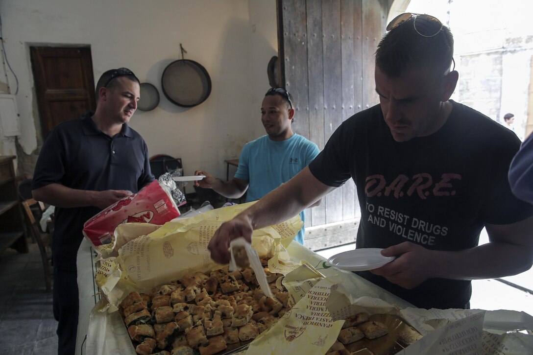 Lance Cpl. Chuck Locasto, a basic landing support specialist with Special Purpose Marine Air-Ground Task Force Crisis Response-Africa, grabs some bread and snacks after a community relations project in Vizzini, Sicily, Sept. 7, 2016.  Marines volunteered to clean up a local historic site and build fences during a community relations project.  (U.S. Marine Corps photo by Cpl. Alexander Mitchell/released)